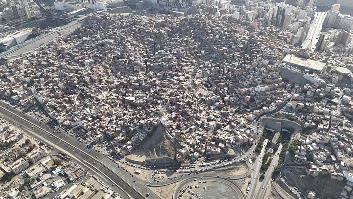 Aerial view of dense unplanned neighborhoods in Makkah before clearance, illustrating architectural security challenges near the Grand Mosque.