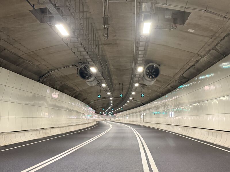 Interior view of the Central Kowloon Bypass tunnel in Hong Kong, showing concrete vaulted ceiling, ventilation systems, and lane markings under artificial lighting.