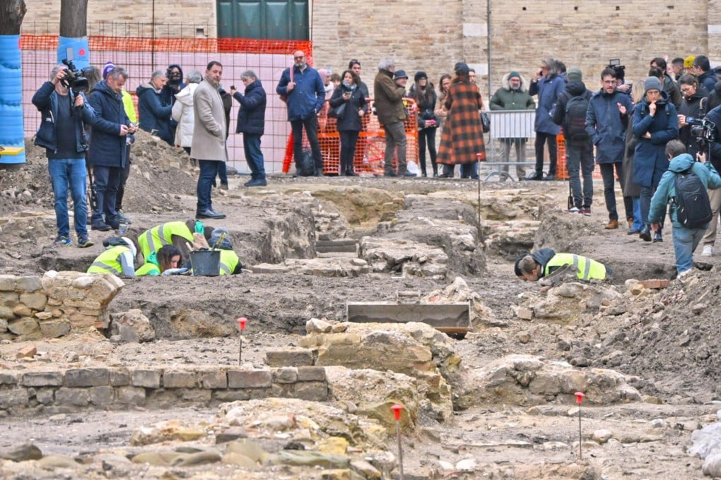 Archaeologists work in the excavation trenches of the ancient Roman public building in Fano, as officials and press observe the historic discovery