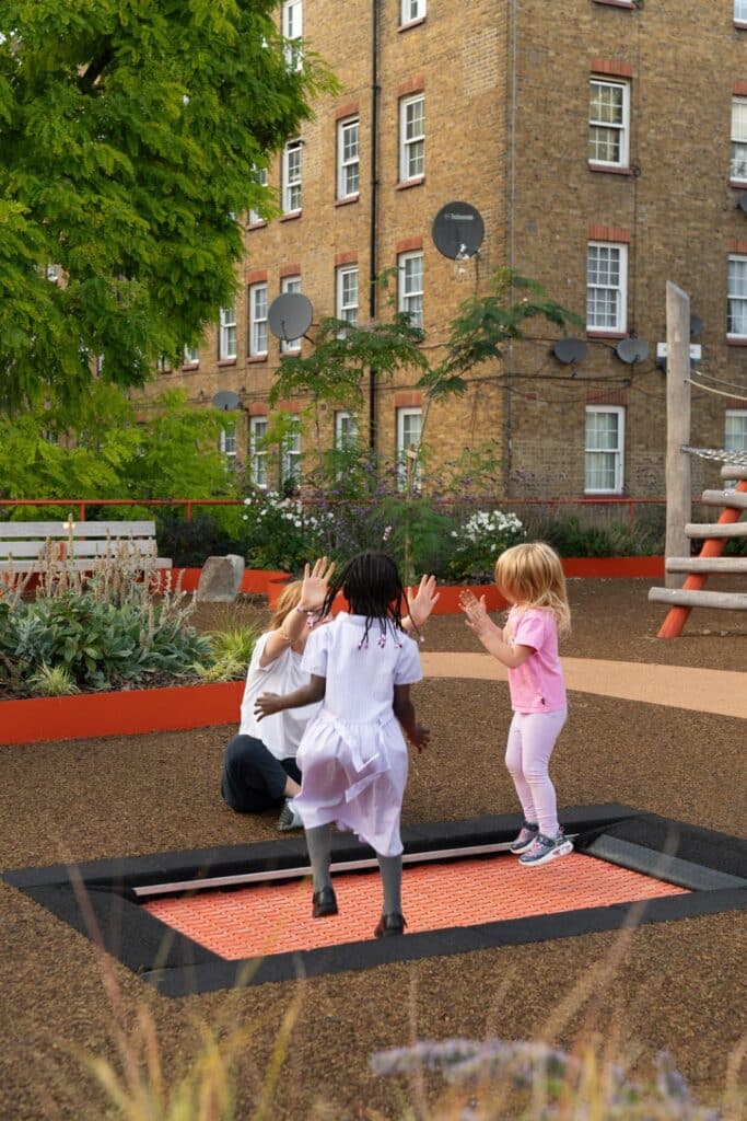 Children joyfully playing on the wheelchair accessible in ground trampoline at Frederick Adventure Playground, a key feature for inclusive play.