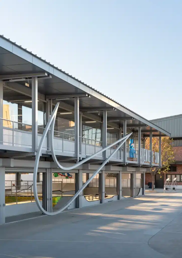Modern steel pavilion at the Coastal Skatepark in Qinhuangdao, featuring a large cantilevered roof, glass facade, and sculptural staircase designed for flexible programming and climate response.
