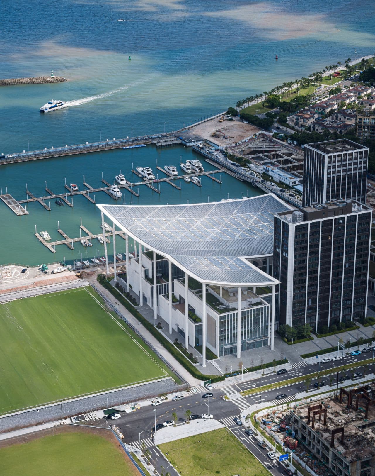 Eye-level view of the main terminal building at Jiuzhou Bay Port, featuring its expansive, wave-like roof structure and glass curtain wall facade.