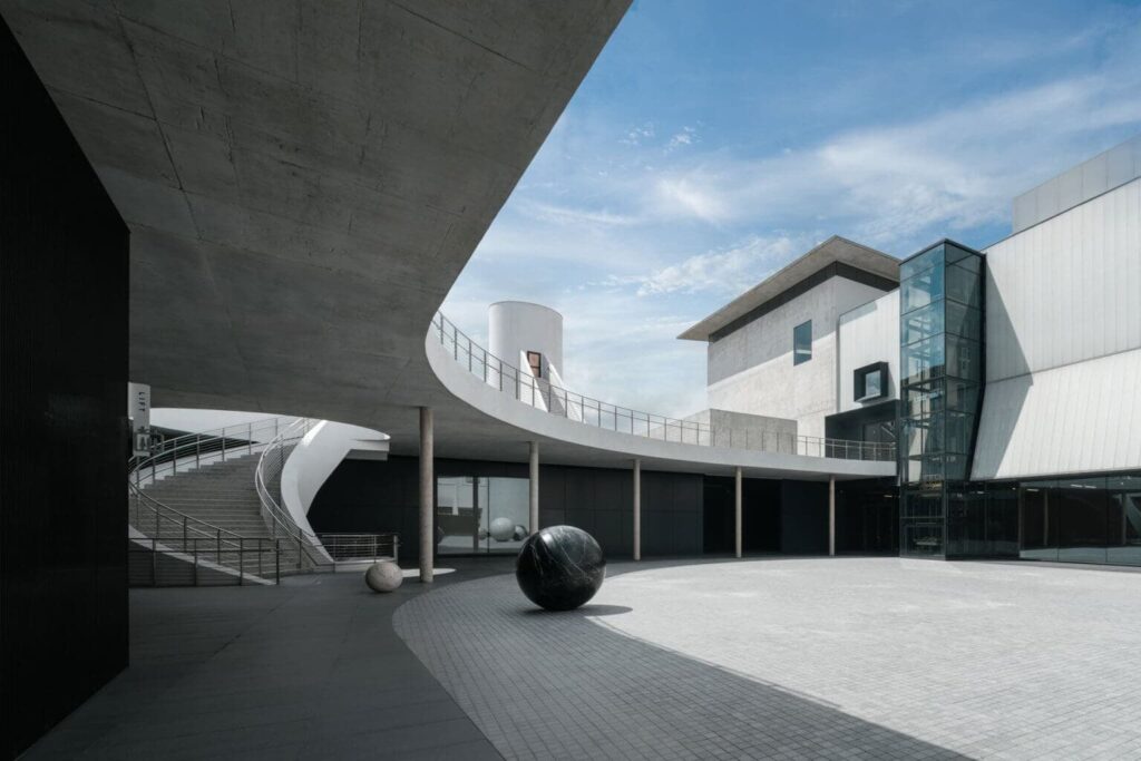 First international contemporary art museum in Bangkok courtyard with curved concrete staircase and sculptural spheres