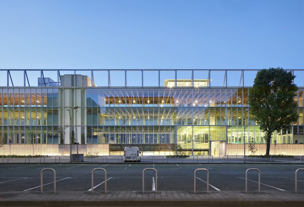 منظر مسائي لمرآب نيلز بور في لوند، السويد، يظهر واجهته الزجاجية الشفافة وهيكله الصلبي المكشوف مع إضاءة داخلية مرئية. ضمن جائزة العمارة الأوروبية 2026