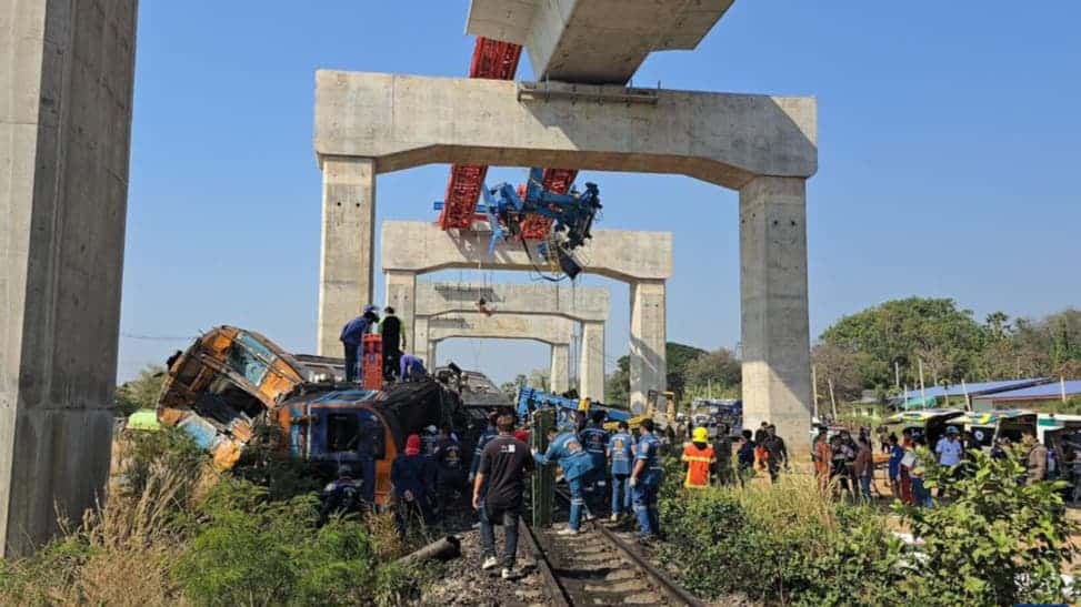 Rescue personnel and onlookers gather at the site of a crane collapse onto a derailed train beneath unfinished high-speed rail viaducts in Nakhon Ratchasima, Thailand, 2026.