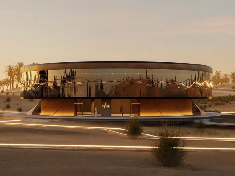 Clio House at dusk: circular desert pavilion with reflective facade and illuminated pathways, showcasing its integration into Dubai’s Margham Desert landscape.