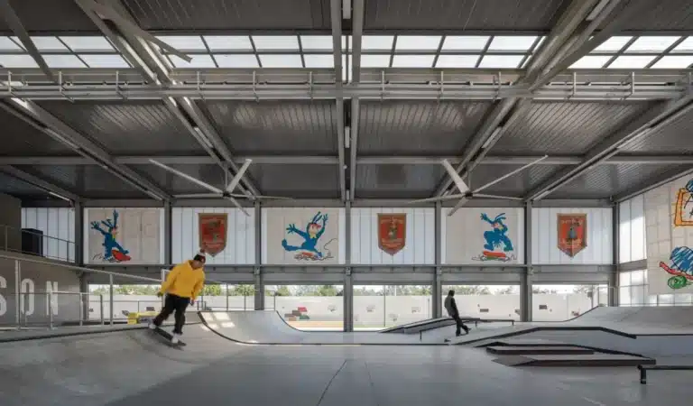 Indoor skatepark at the Coastal Skatepark in Qinhuangdao, featuring high-span steel structure, translucent roof panels, and graffiti murals designed for year-round training without surveillance hardware.