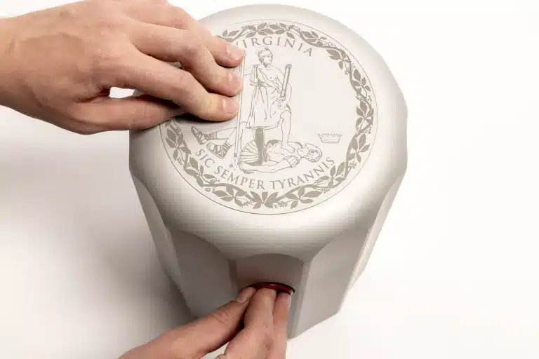 Human hands sealing the base of the  250th anniversary, with Virginia state seal visible on top, designed by Norman Foster.
