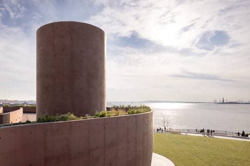 Pavilion&rsquo;s cylindrical concrete tower and curved retaining wall overlook New York Harbor, with visitors enjoying waterfront views under a bright sky showcasing flood-resilient landscape architecture.