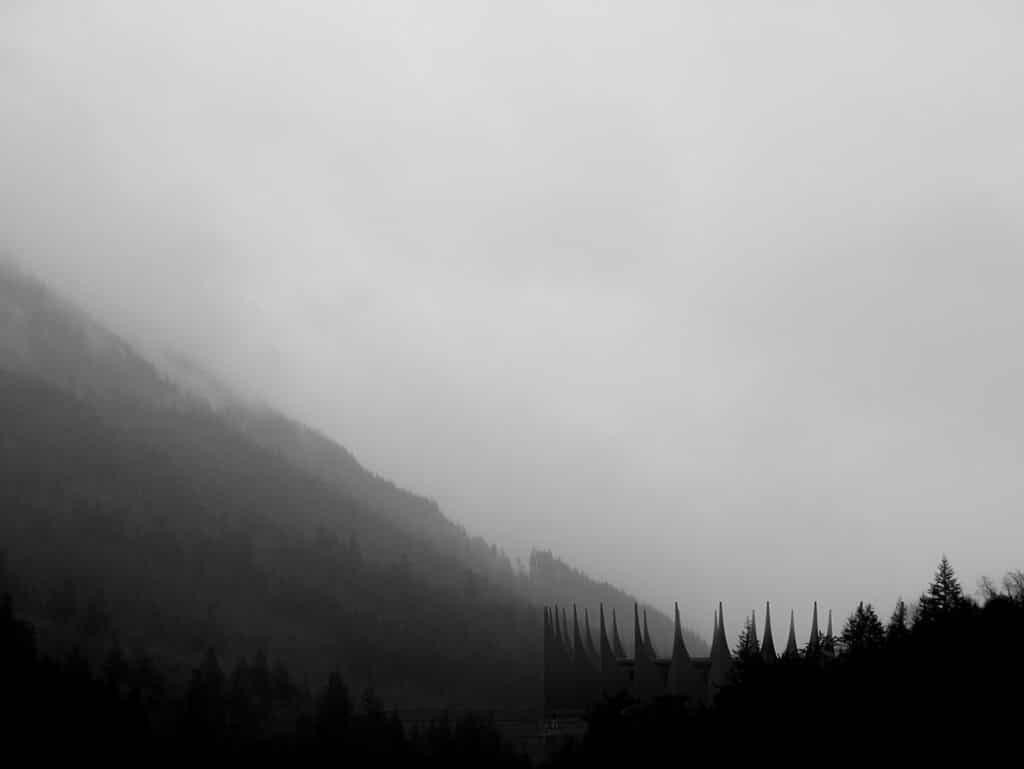 A black and white silhouette of the Lynx drone station's spiky architecture against a foggy mountain range