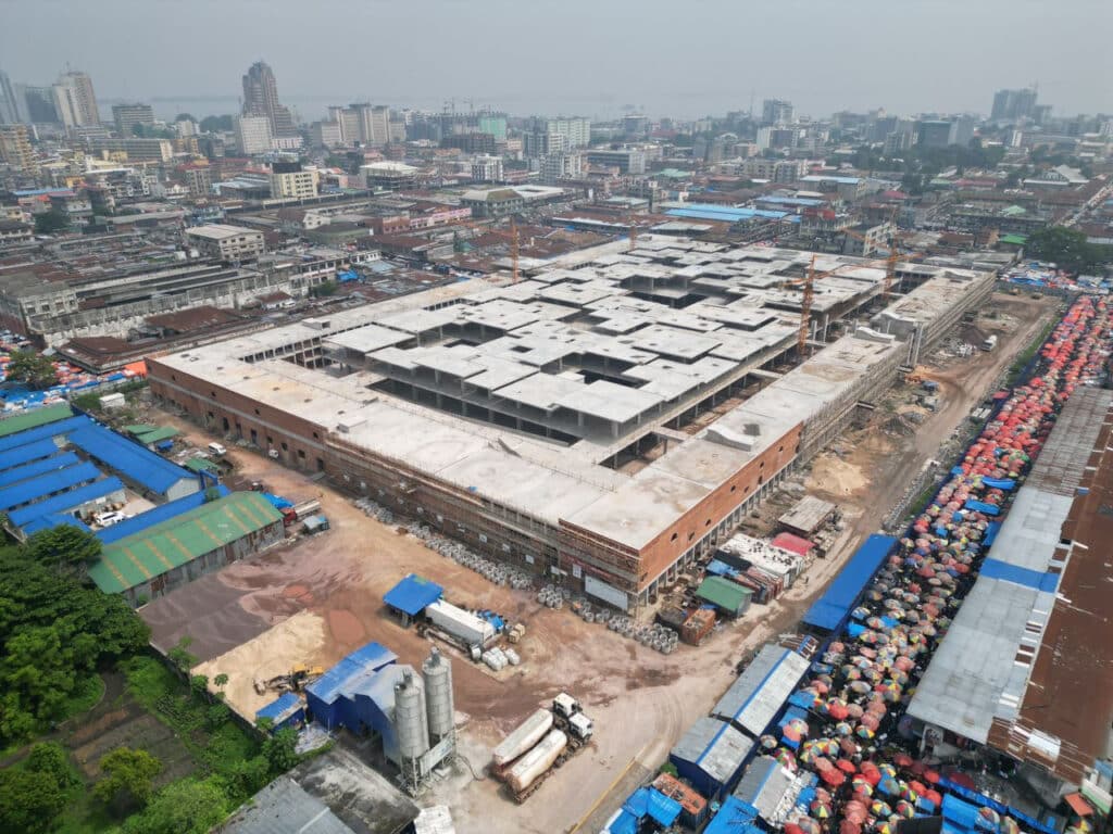 Wide shot of the Zando Central Market's exterior, illustrating the scale of the redevelopment and the repetitive rhythm of its concrete and brick structure.
