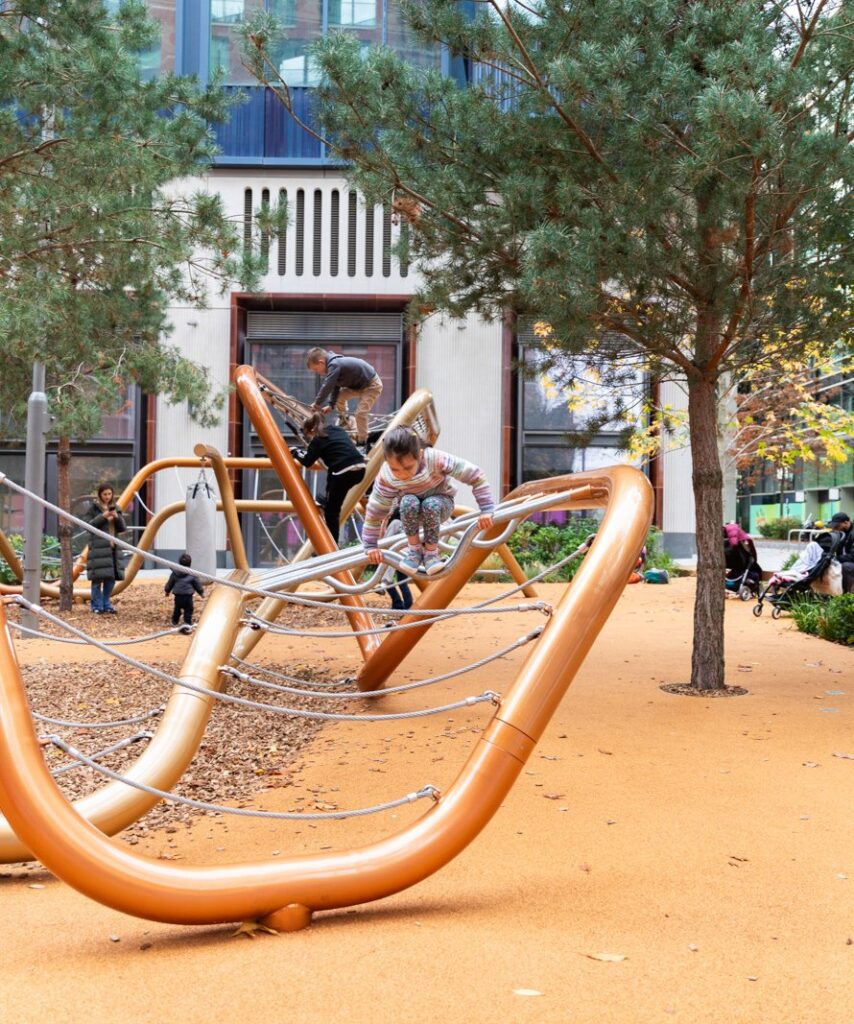 Children climbing on the dynamic, curved metal and rope climbing structure at the Frederick Adventure Playground, designed for multi group use.