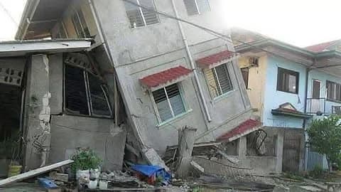 Seismic-resistant design failure: a residential building tilts severely after an earthquake, showing structural collapse in non-reinforced concrete.