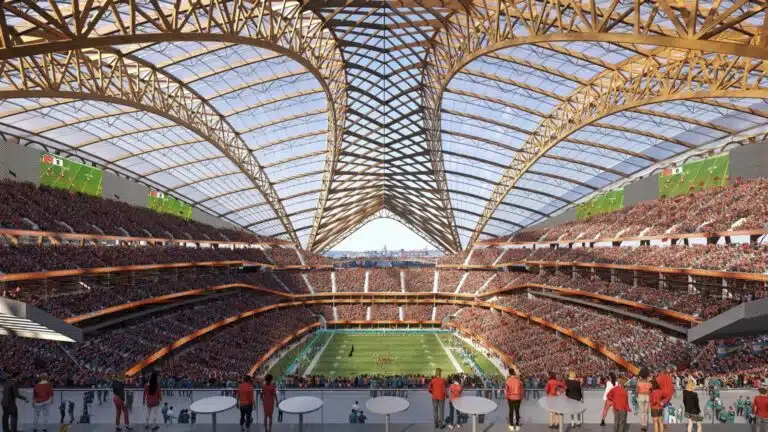Aerial view of Washington’s New NFL Stadium concept at twilight, showing translucent roof and surrounding urban development near Anacostia River.
