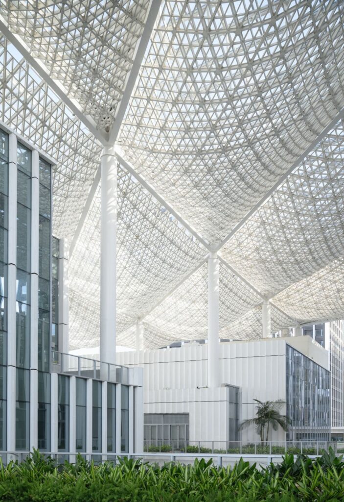 Interior view of the main concourse at Jiuzhou Bay Port's transit hub, showcasing the vast, column-free space and intricate ceiling structure.
