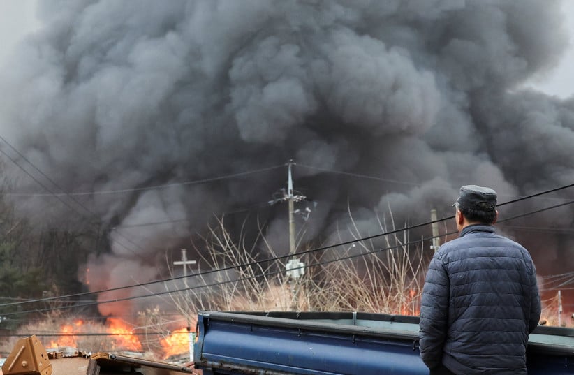 A man watches as thick black smoke billows from the January 2026  fire in  Village, Seoul a stark visual of urban neglect where informal housing burns unchecked due to lack of fire safety infrastructure.