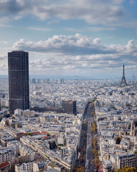 The original Tour Montparnasse in Paris, a dark monolithic skyscraper, seen against the city skyline with the Eiffel Tower in the background, representing the "before" state of the complex.