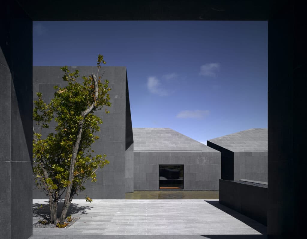 A brick building with a large arched window, the Faith Museum by N&iacute;all McLaughlin, winner of the 2026 RIBA Royal Gold Medal.