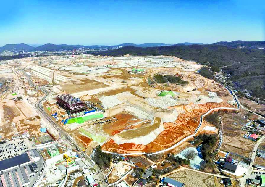 Aerial view of the expansive construction site for Korea’s largest semiconductor complex in Yongin, showing land grading, early structures, and surrounding hills under clear sky.
