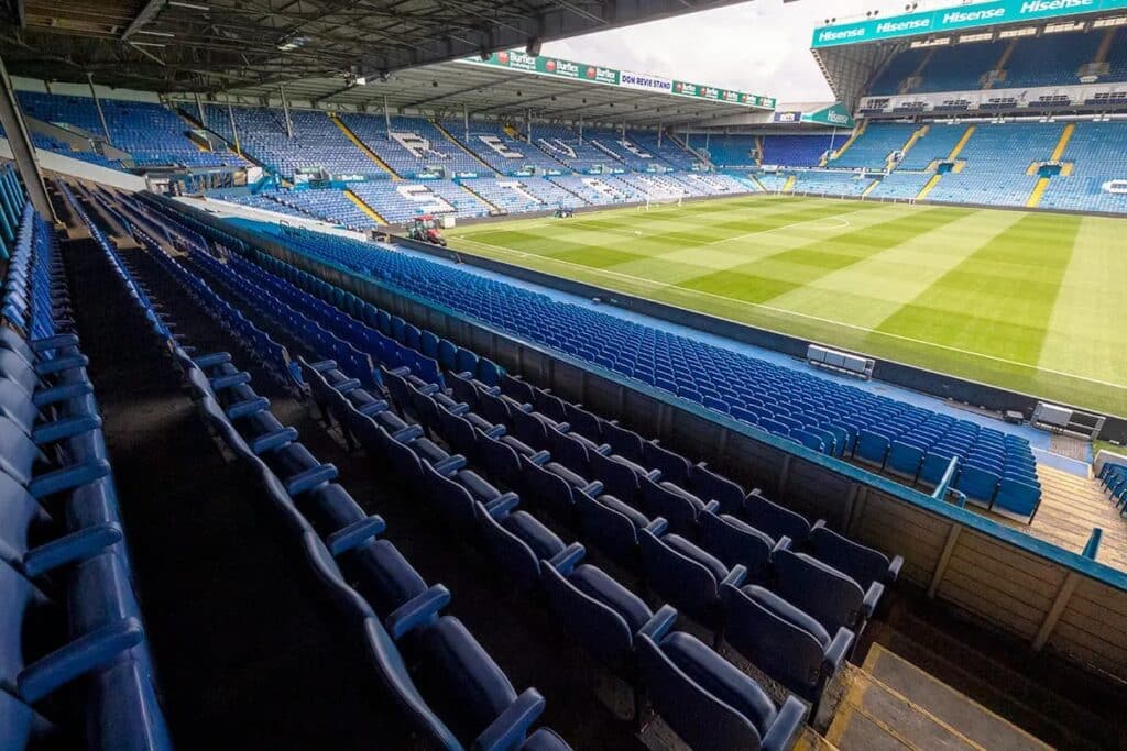 Interior view of  Road stadium before expansion, showing blue seating rows and pitch maintenance under roof structure.