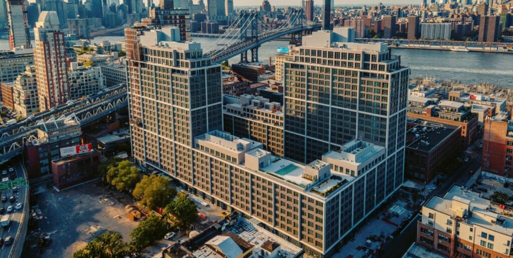 Aerial view of a large mixed-use residential and commercial complex in Brooklyn, adjacent to the Manhattan Bridge and East River, showcasing urban density and contextual integration. 
Architectural Innovation