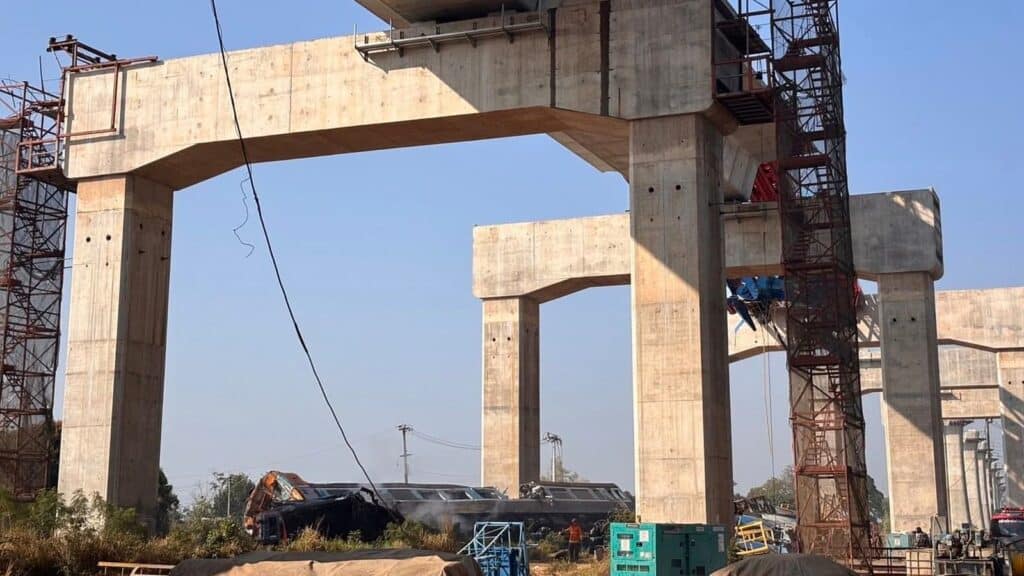 Collapsed crane and derailed train beneath unfinished concrete viaducts at a high-speed rail construction site in Nakhon Ratchasima, Thailand, 2026.