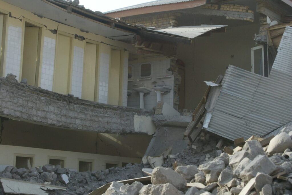 Severe structural failure of a multi-story building after the Kashmir earthquake, showing a collapsed floor and exposed internal rooms.