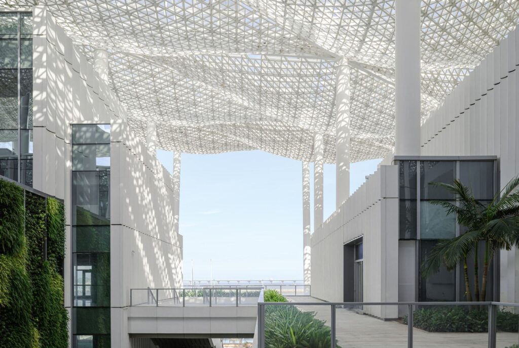 منظر للممشى البحري العام في ميناء خليج جيوتشو، حيث يستمتع المشاة بالمساحة أمام المباني الحديثة متعددة الاستخدامات.