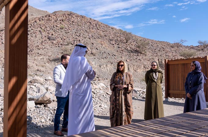 تشاهد الشيخة بدور القاسمي موقع نوماد كلباء خلال زيارة تفتيشية قبل الافتتاح، وسط فريق العمل أمام التضاريس الصخرية  إعادة الاستخدام البيئي في مراقبة المشاريع.