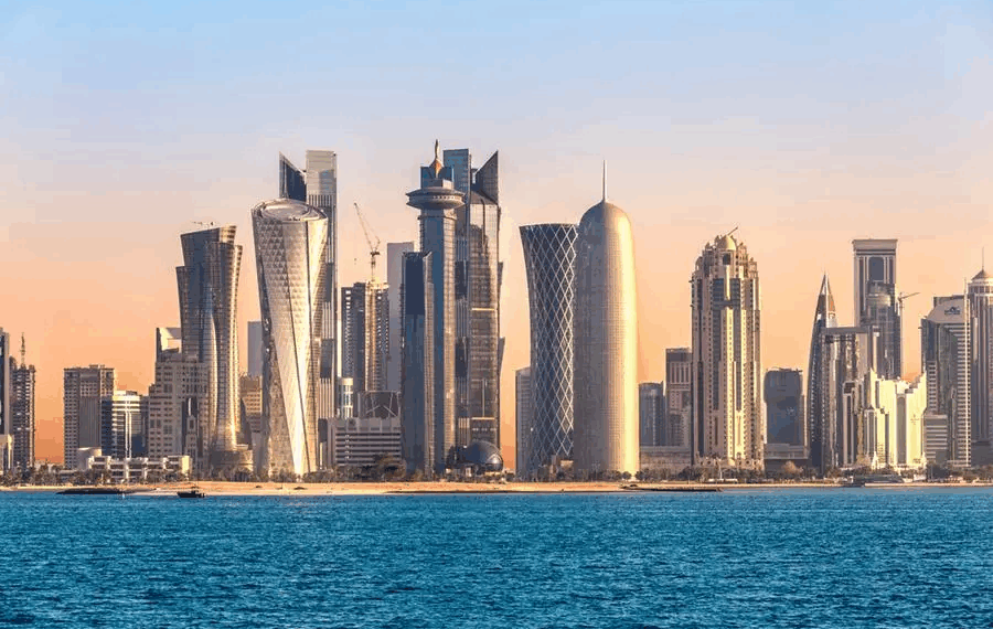 Modern skyline of Doha, Qatar, featuring iconic skyscrapers like the Burj Doha and Tornado Tower along the Persian Gulf coast during sunset.