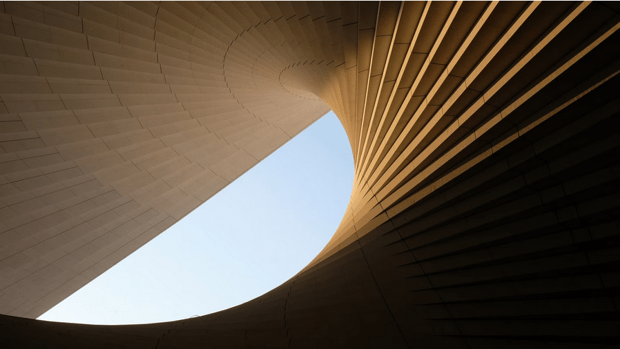 An exterior view of the Shanghai Grand Opera House in China, featuring its iconic white helical roof design that resembles an unfolding fan, set against a clear sky