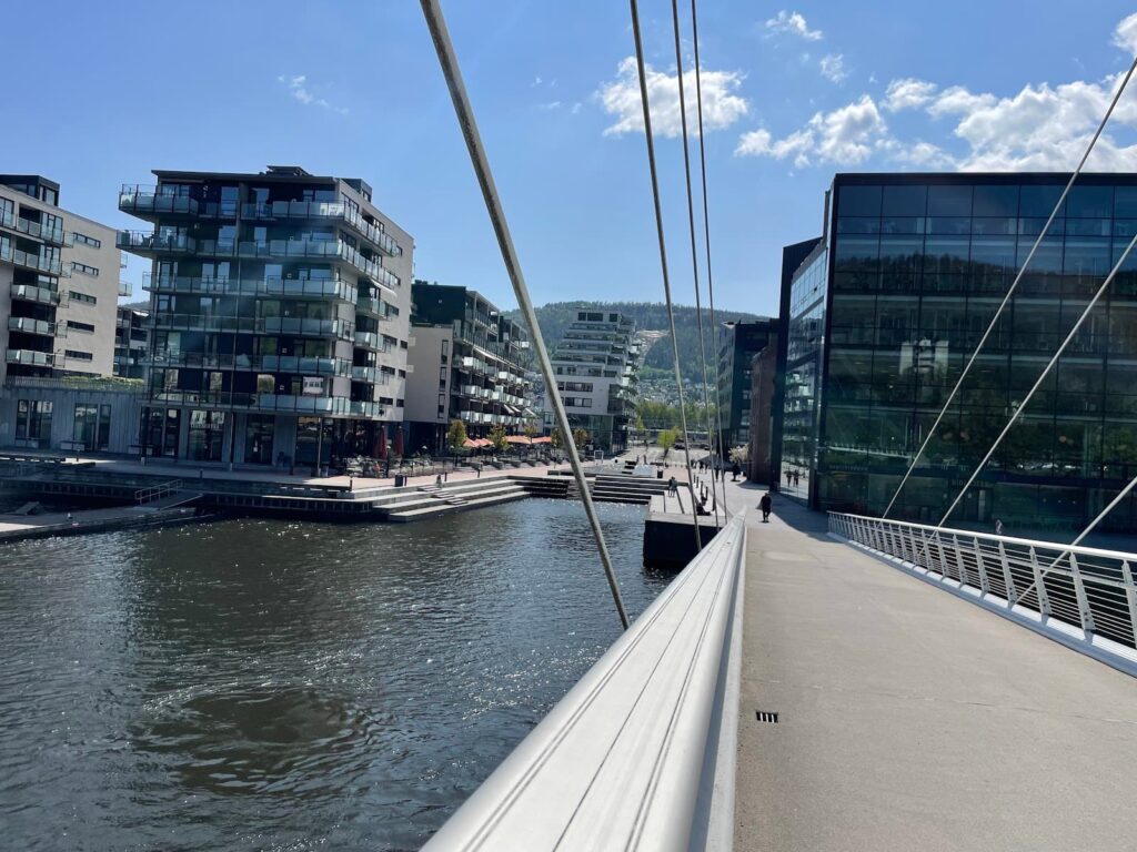 Pedestrian bridge over the Drammenselva River, connecting modern residential and office buildings in downtown Drammen, Norway.