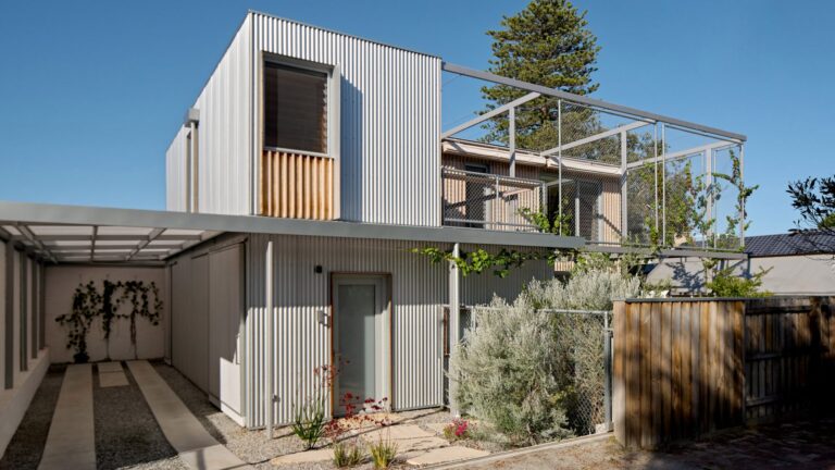 Modern two-story house with corrugated metal cladding, a grey steel pergola, and a gravel driveway in Perth.