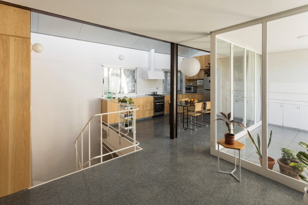 Open plan kitchen and dining area in an upper floor PH apartment featuring granite mosaic flooring and large glass doors.