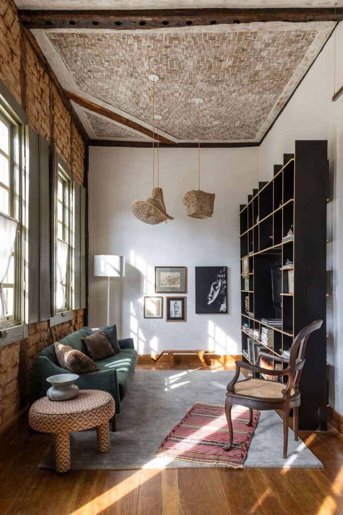Sunlit living room of Heloisa and Leonardo House showing a blend of mid-century modern furniture and rustic architectural details.