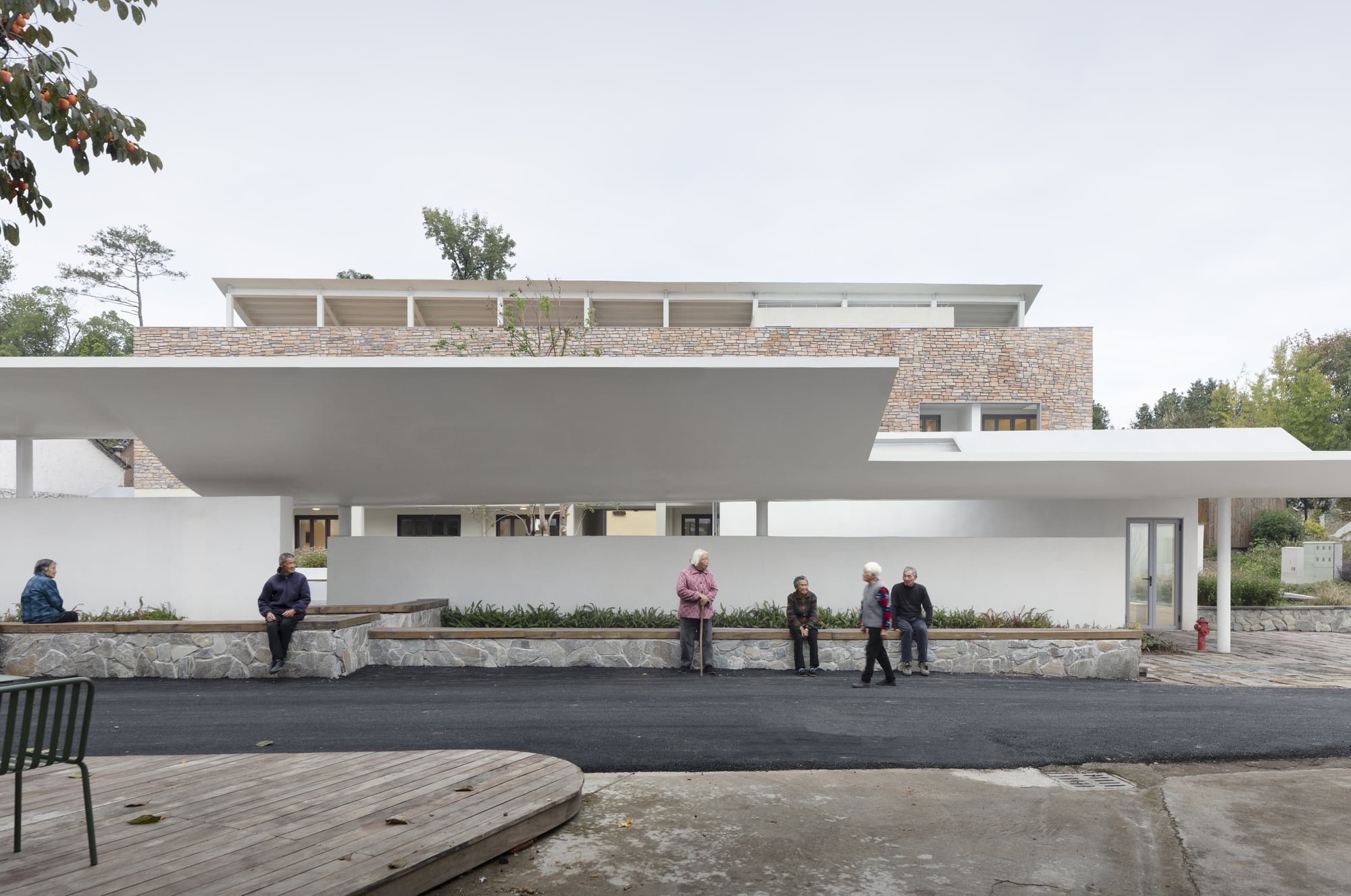 Local villagers sitting on stone benches under the long white eaves of Qingyi Lodge.