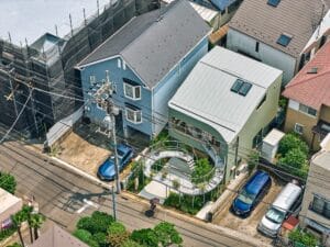 Aerial perspective of a green modern house in Tokyo featuring a unique curved steel terrace called Kazari Garden in a dense residential area.