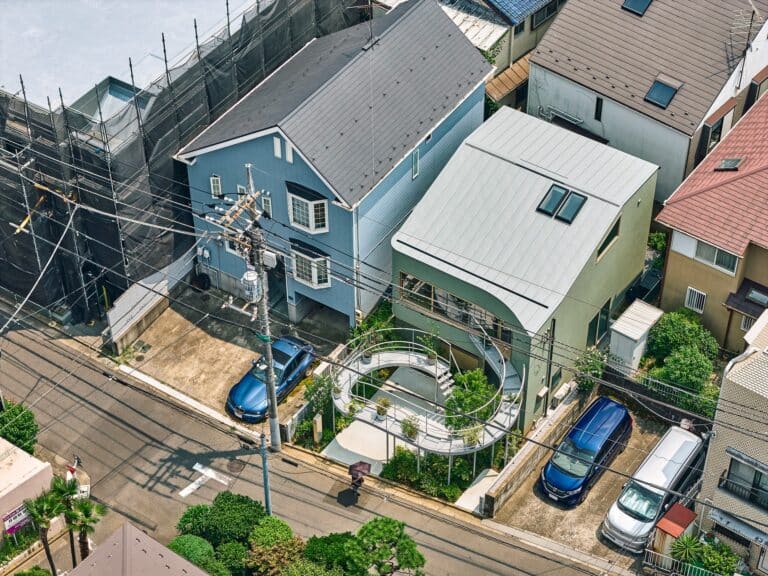 Aerial perspective of a green modern house in Tokyo featuring a unique curved steel terrace called Kazari Garden in a dense residential area.