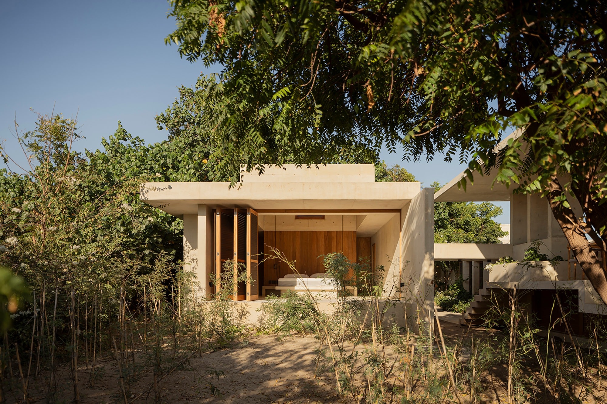 Exterior of a standalone bedroom pavilion in Casa Ohana, nestled within dense tropical vegetation and featuring a flat concrete roof.