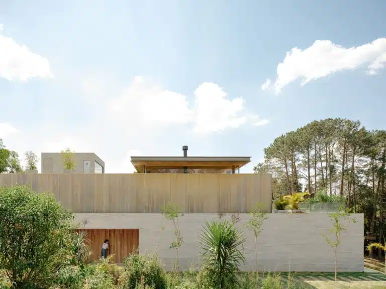 Modern facade of Casa CR JL featuring a concrete base, Accoya wood cladding, and a minimalist wooden entrance door.