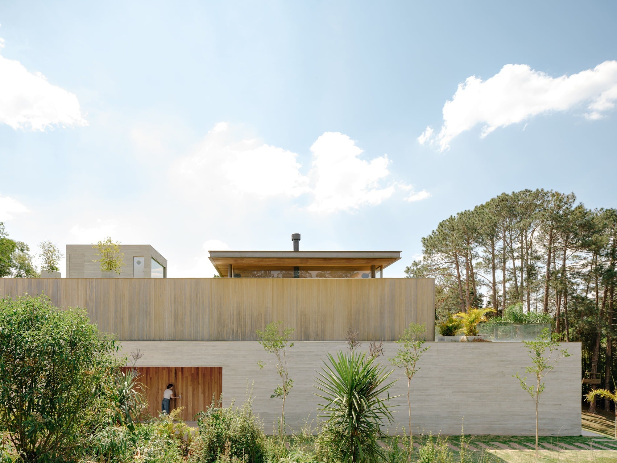 Modern facade of Casa CR JL featuring a concrete base, Accoya wood cladding, and a minimalist wooden entrance door.