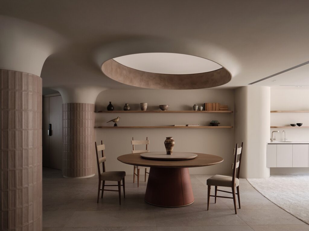 Round wooden dining table under a circular ceiling cove in C.S.C Residence with textured pillar details.