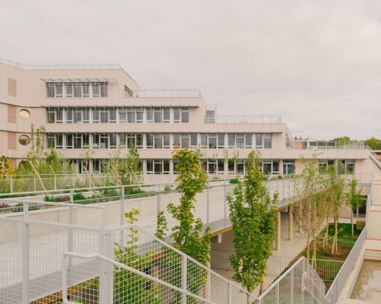 Vertical stepped architecture of Dominique Frelaut School with green garden terraces and outdoor metal staircases.