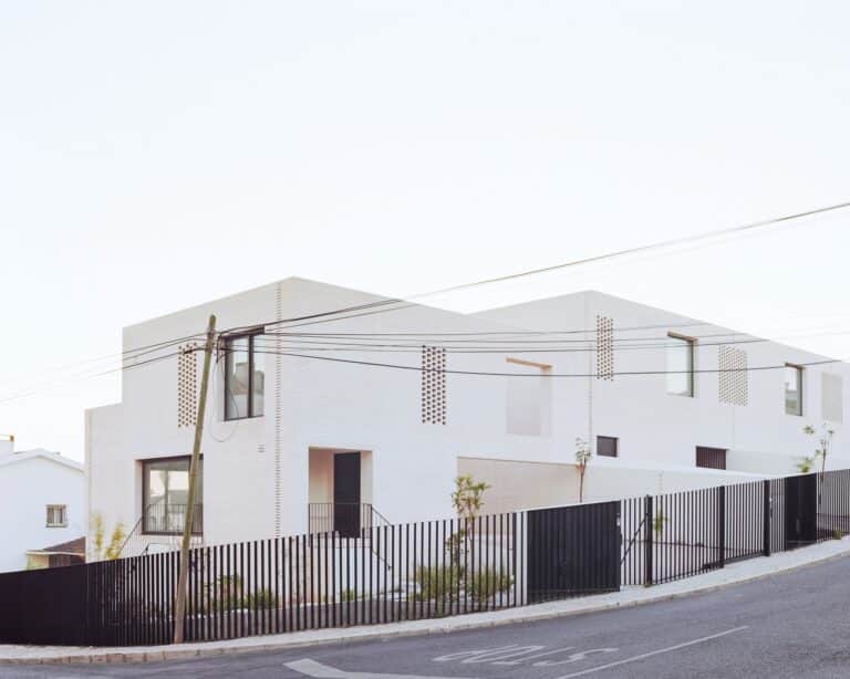 White brick townhouse facade in Porto with black metal fence and street view.