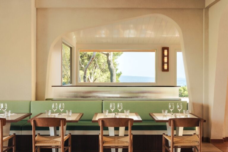 Symmetrical view of a dining table at Le Belvédère restaurant framed by a large window showing trees and the horizon.