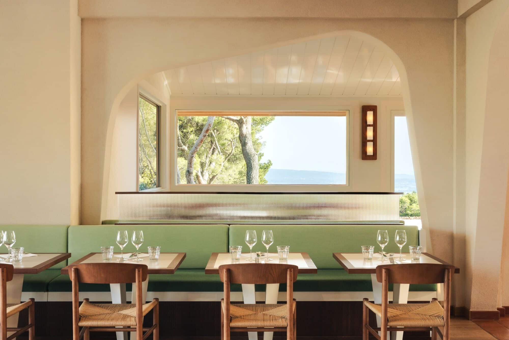Symmetrical view of a dining table at Le Belvédère restaurant framed by a large window showing trees and the horizon.