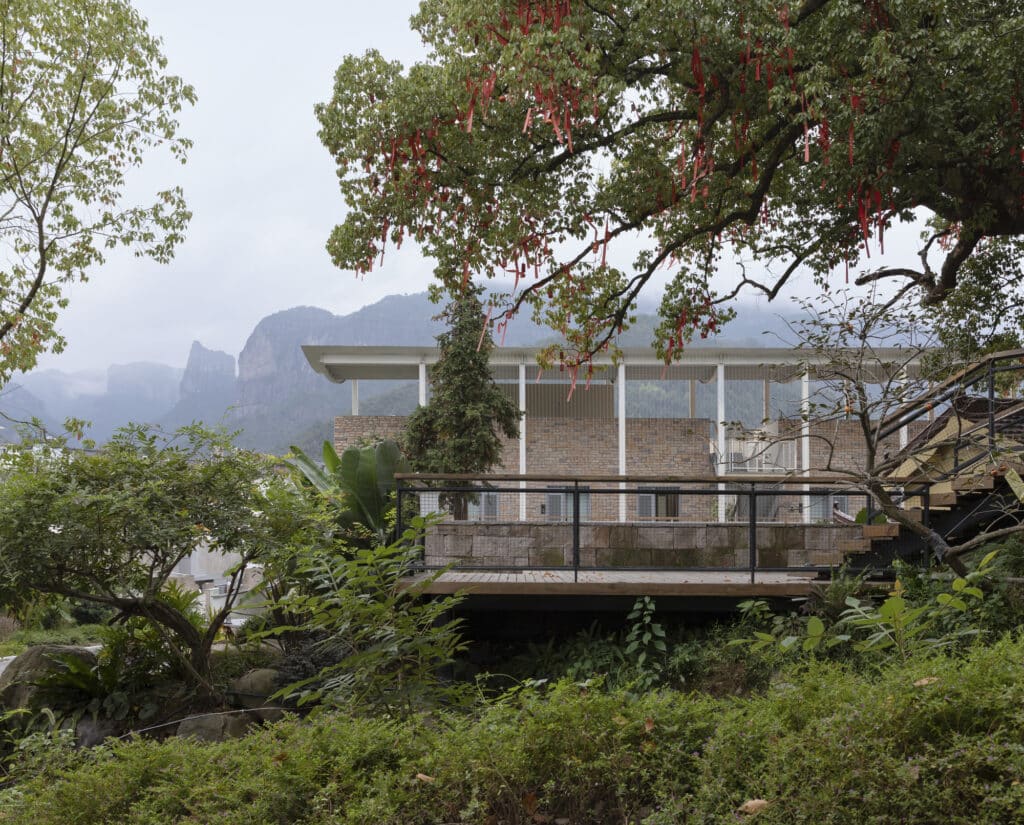View of the Qingyi Lodge building and Fanzheng Peak through the branches of an ancient tree.