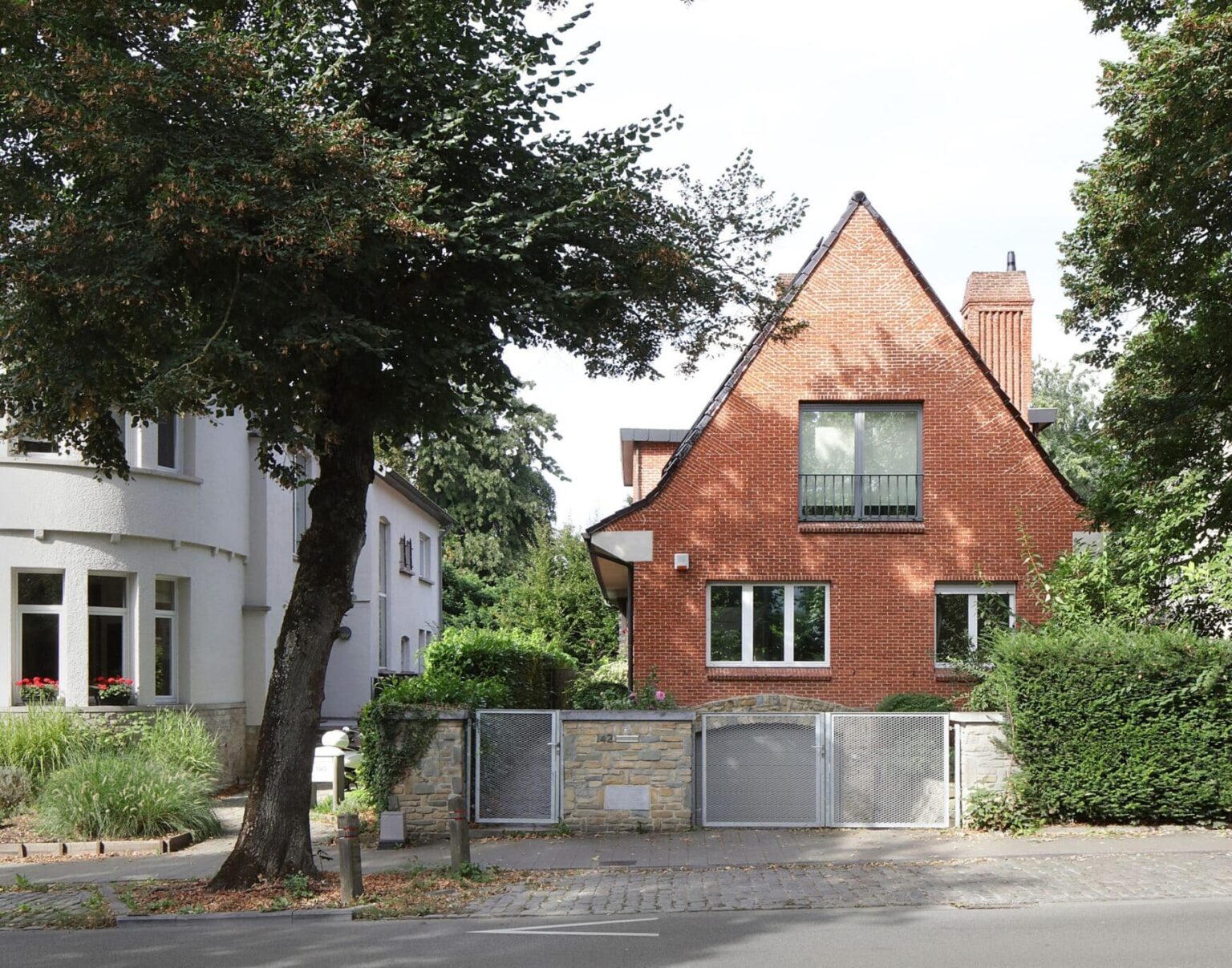 Exterior front view of a traditional red brick house in Brussels with new grey aluminum window frames.