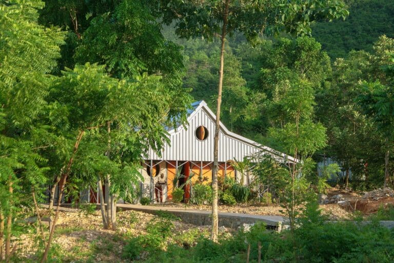Exterior view of the Bercy-Cavaillon Community Center nestled within dense tropical vegetation in rural Haiti.