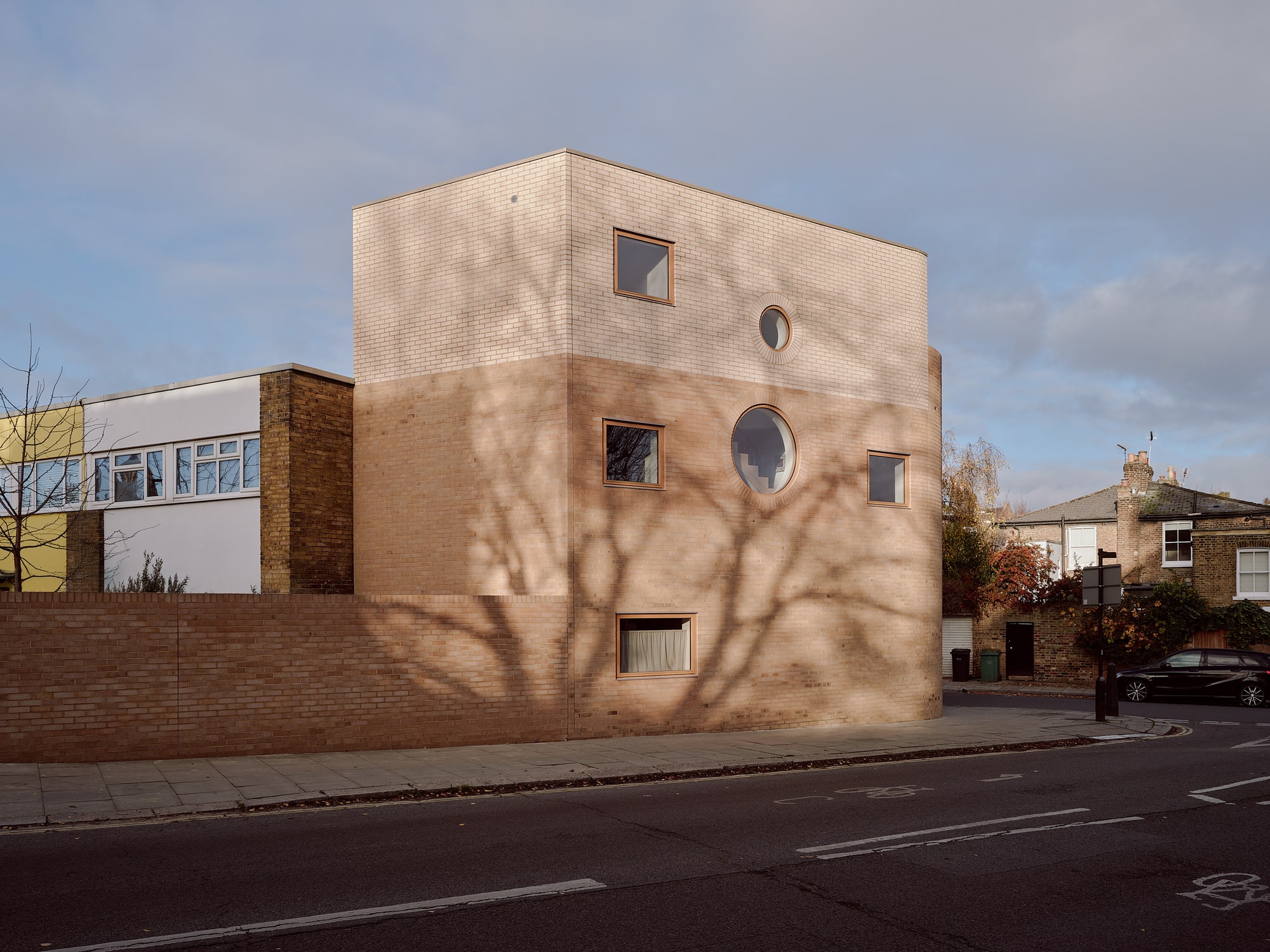 Exterior view of Runda House featuring a dual-tone brick facade with circular and square windows under a soft sky.